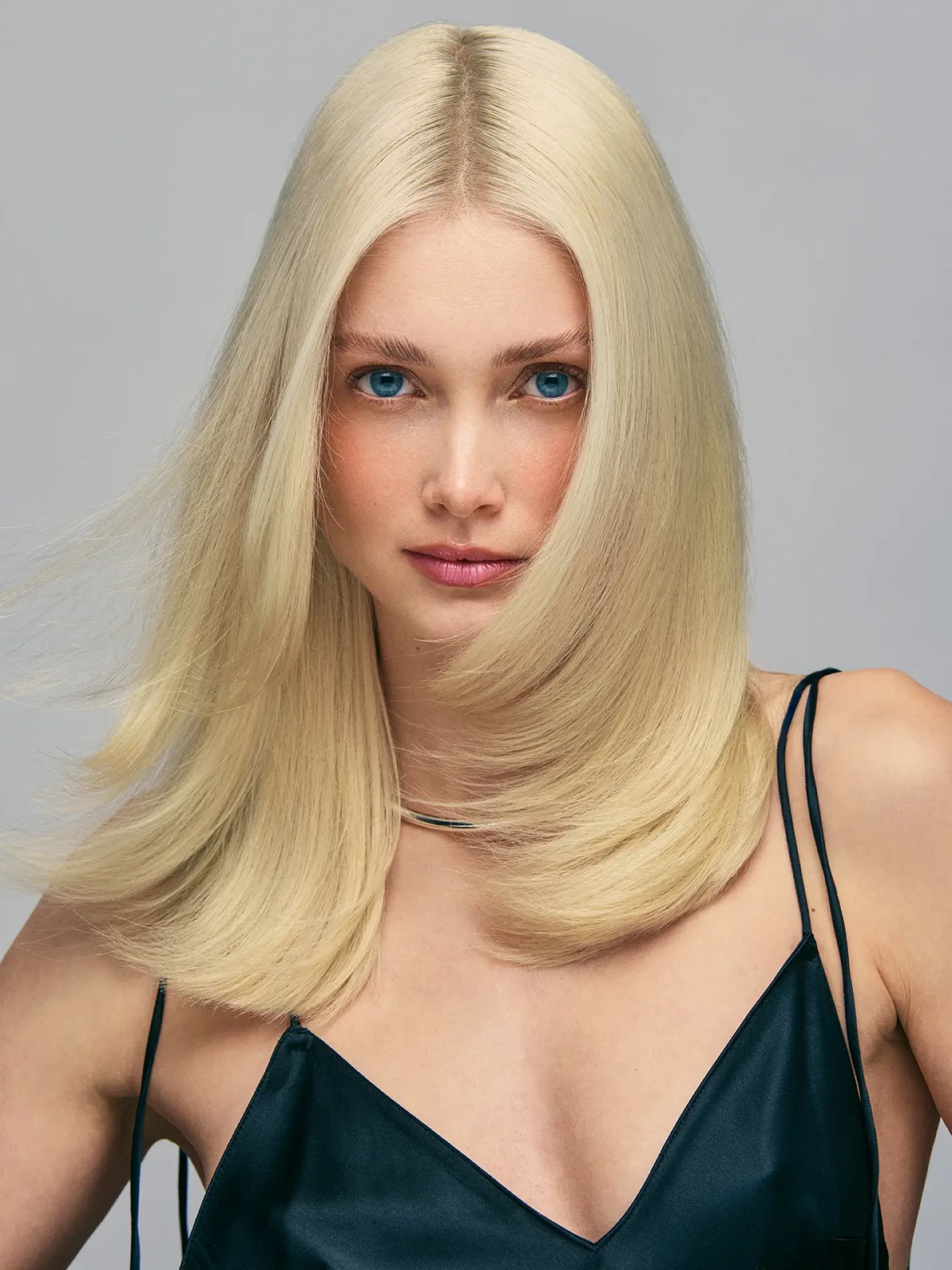 Blonde model with flowing hair wearing a dark sleeveless top in the studio