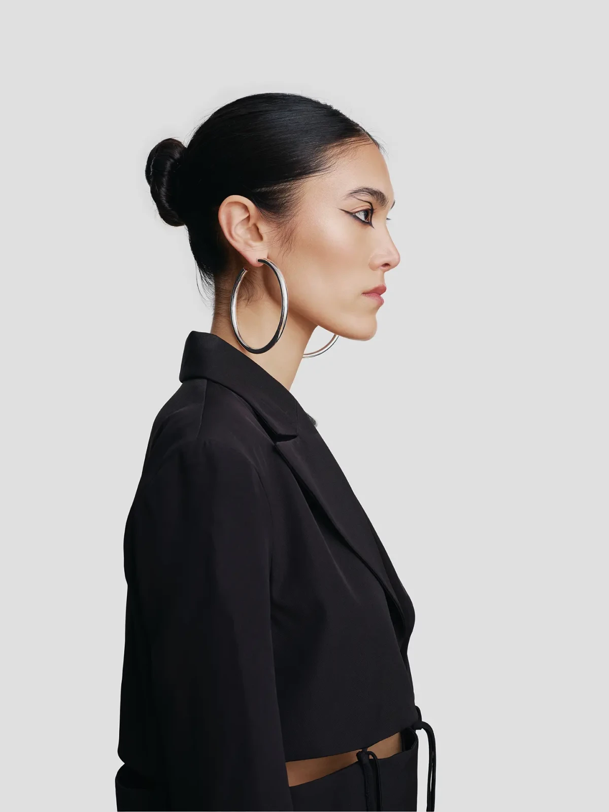 Profile portrait of a model in black tailoring with large gold hoop earrings