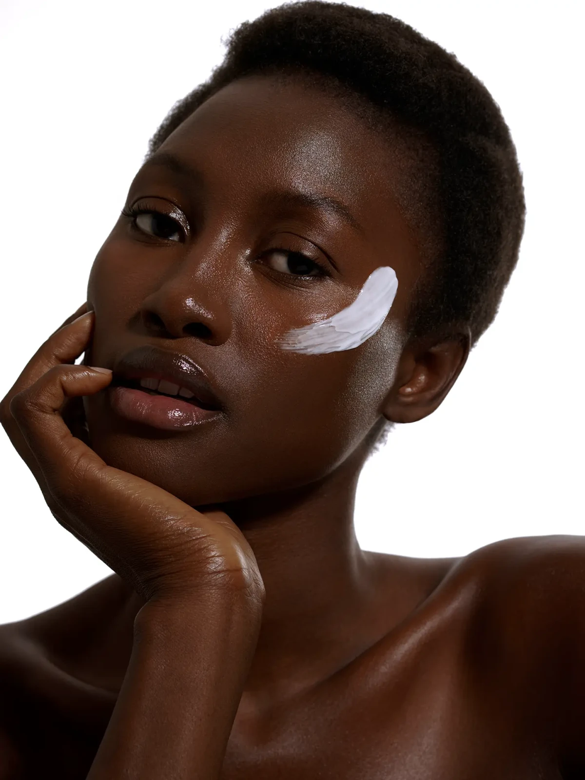 Beauty portrait of a dark-skinned model with white skincare cream on her cheek