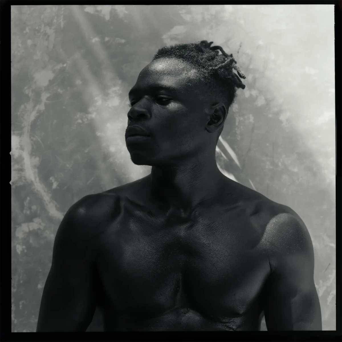 Black-and-white portrait of Kwesi looking to the side against a textured wall
