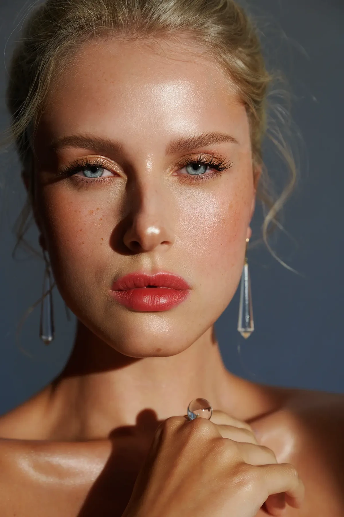 Blonde model with red lipstick and dangling earrings in direct sunlight