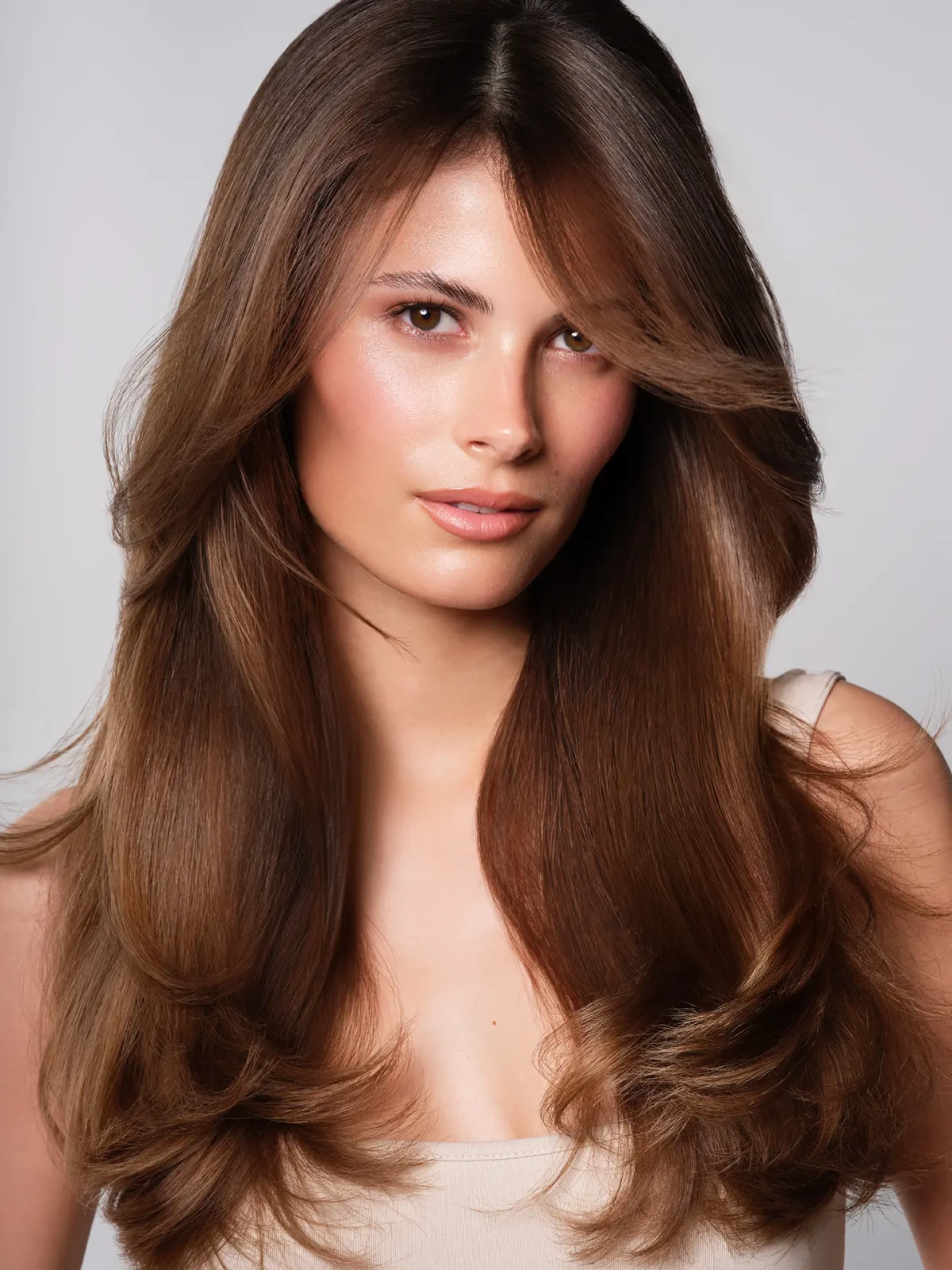 Studio portrait of a brunette model with loose wavy hair and a white top