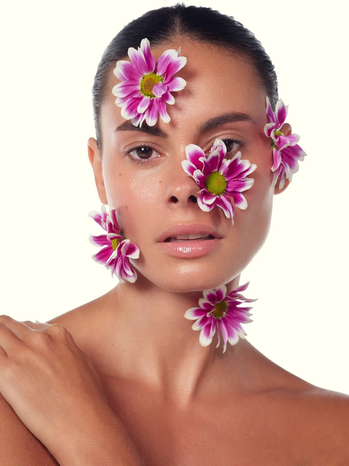Beauty portrait with pink flowers arranged around the model’s eyes and cheek