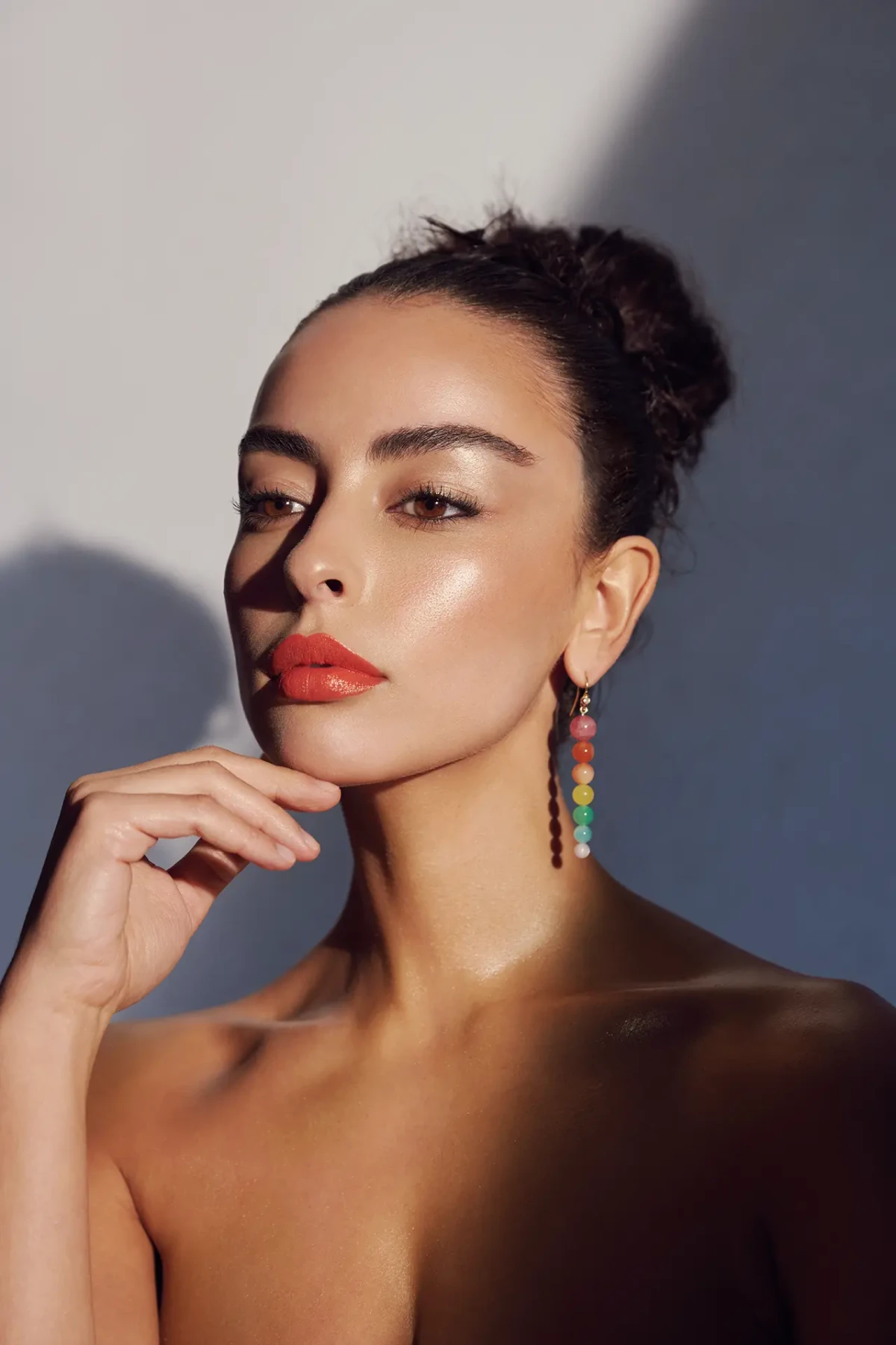 Beauty portrait with red lipstick, dangling earrings and a geometric sunlight shadow