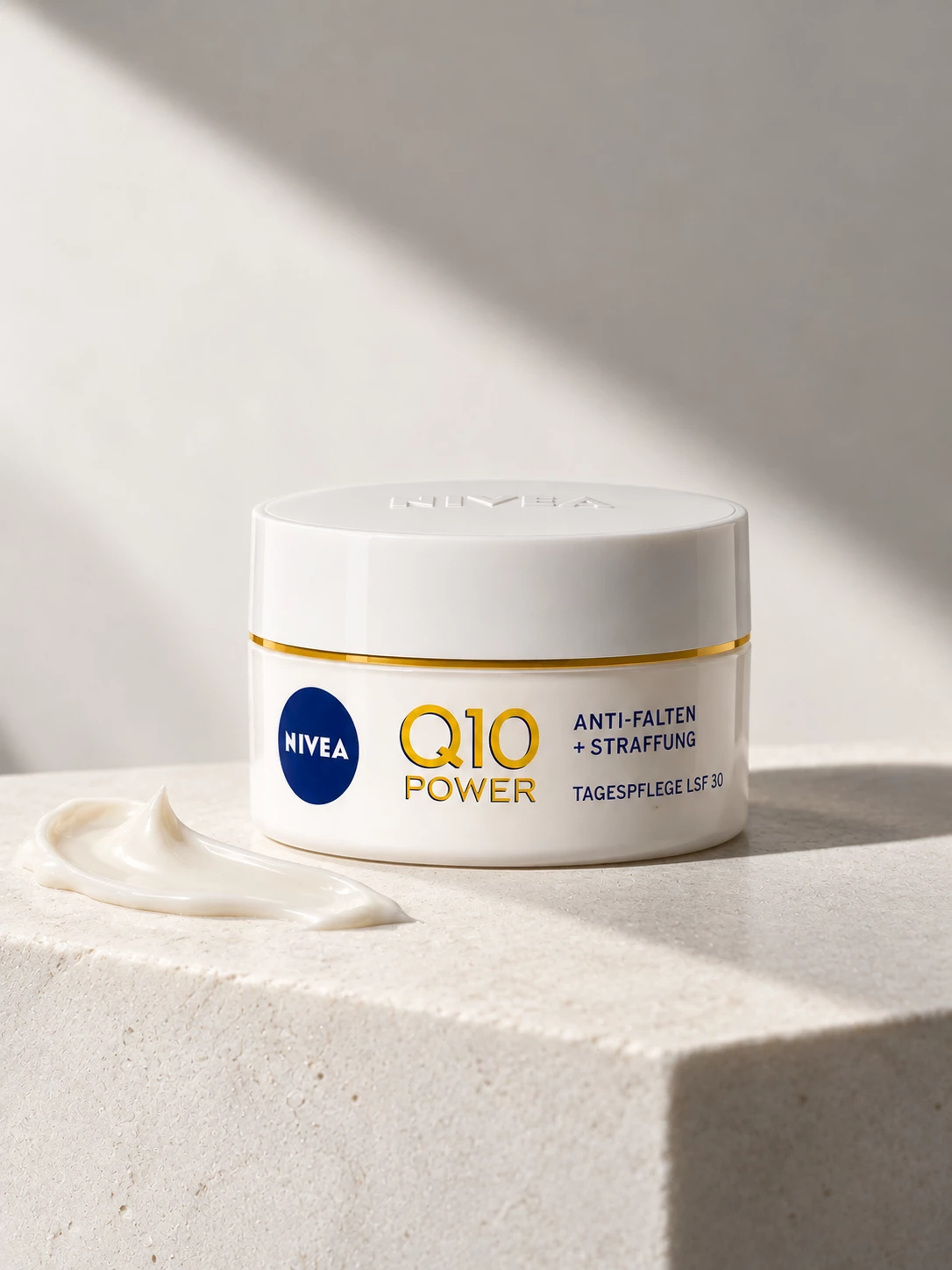 Closed Nivea Q10 Power jar on warm stone with a cream swirl