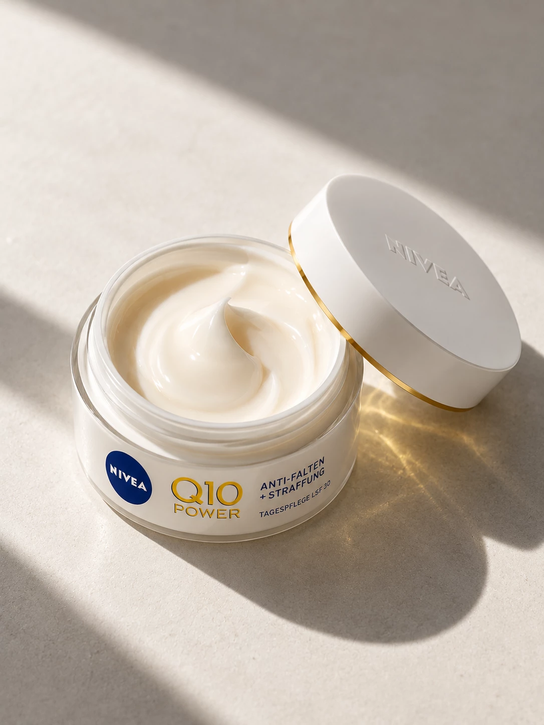Open Nivea Q10 Power jar with cream and tilted white lid