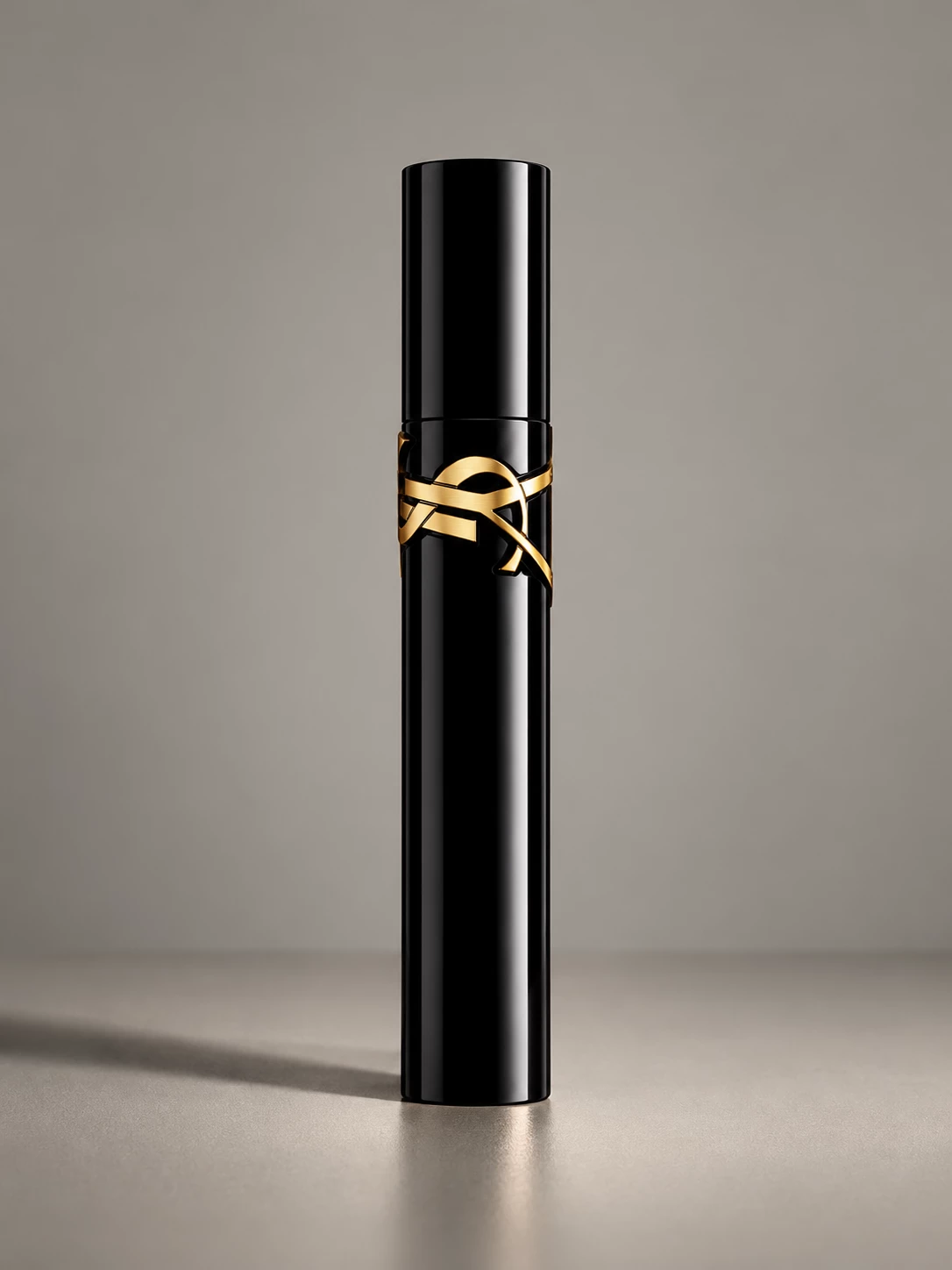 Closed black YSL mascara tube with gold logo on grey