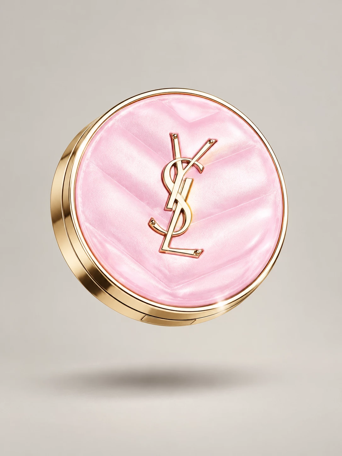 Pink and gold YSL compact suspended against a warm grey background