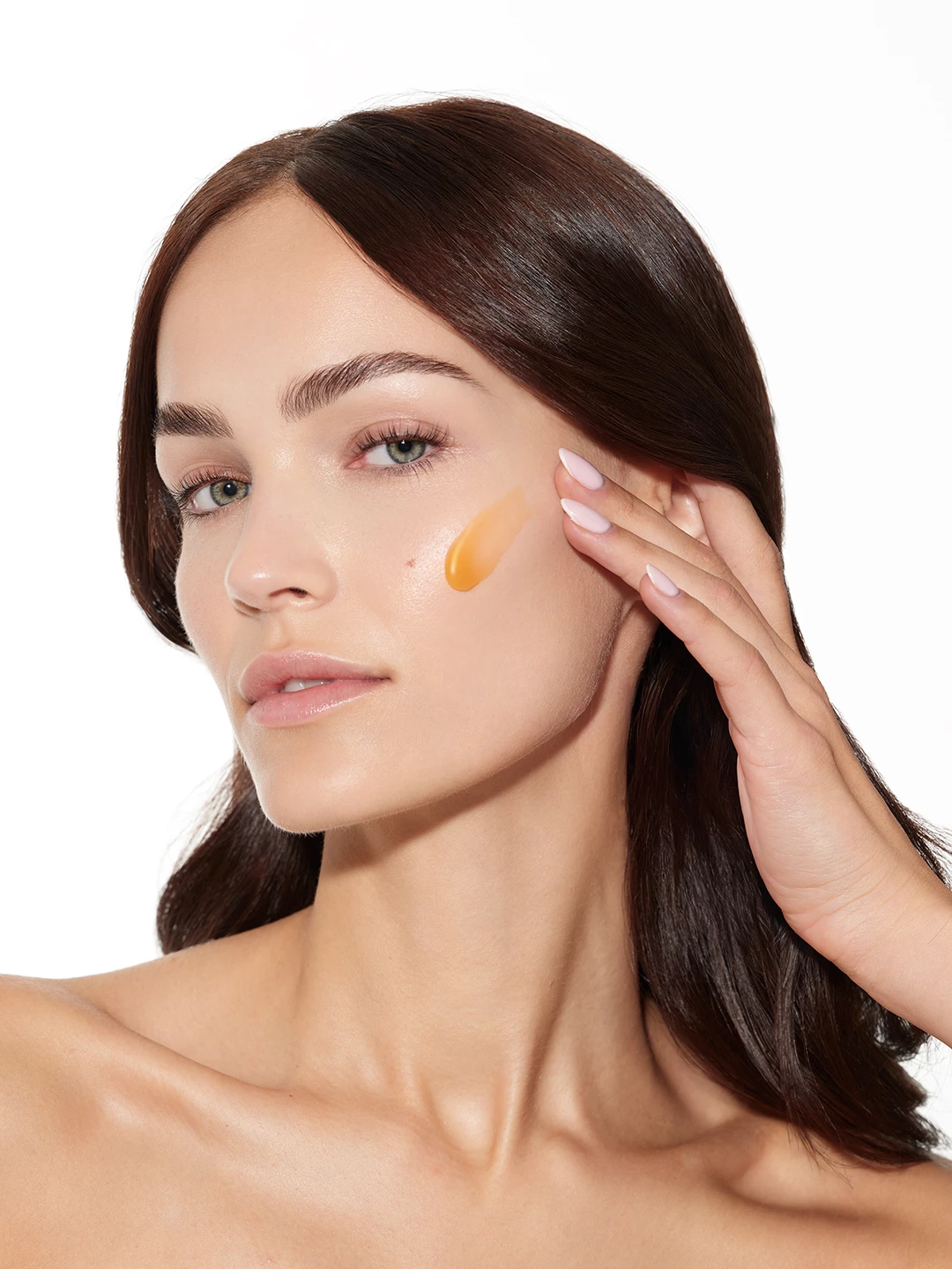 Julia Wess applying an amber serum texture to her cheek