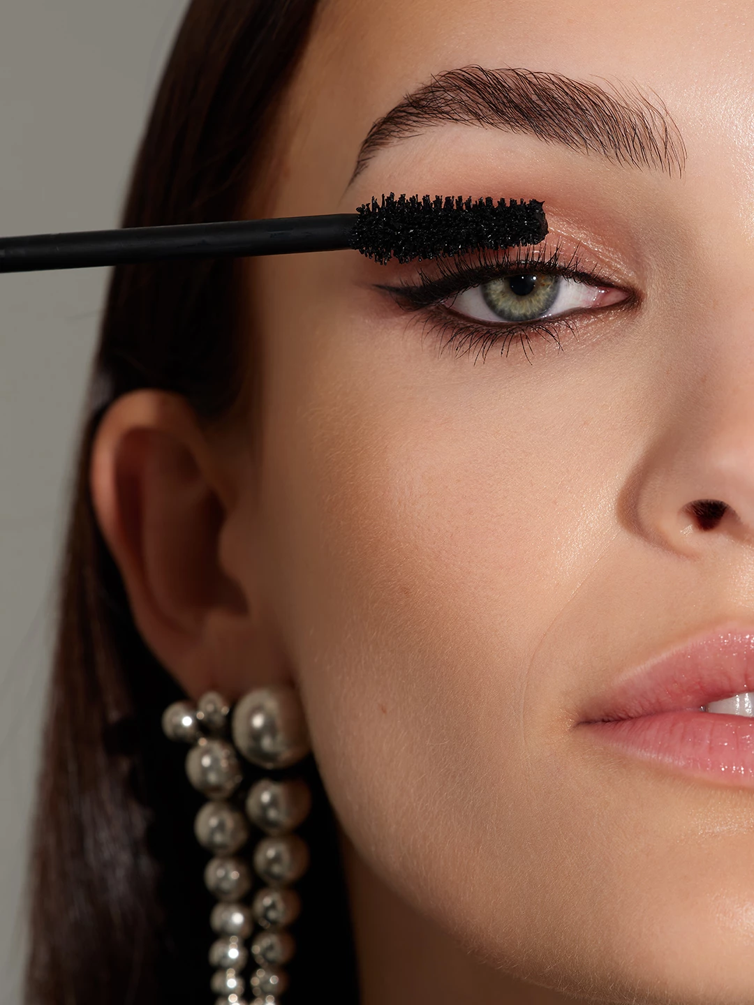 Close-up of mascara application on Julia Wess with silver earrings