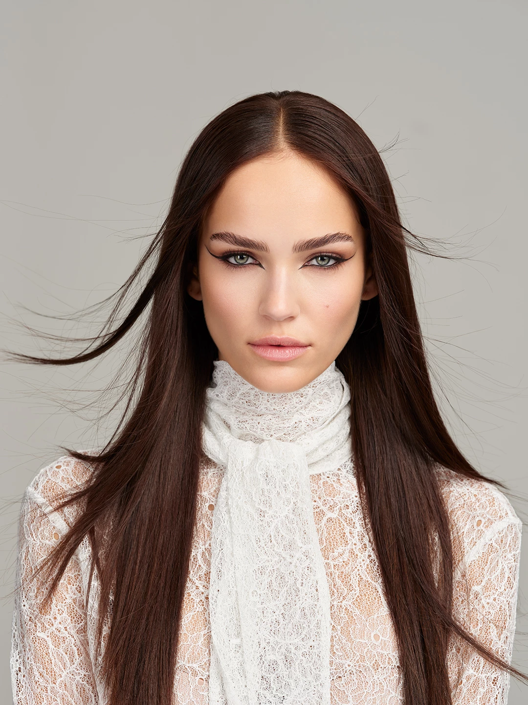 Julia Wess with flowing brown hair in a white lace blouse