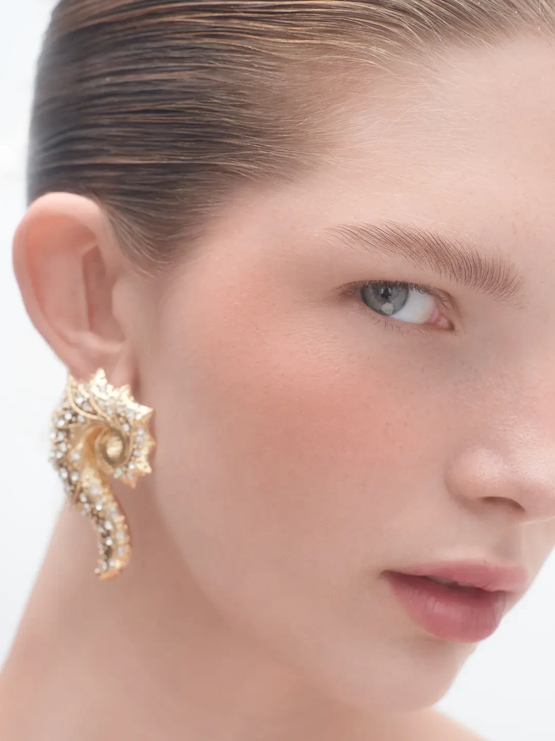Close beauty portrait with slicked-back short hair and a gold statement earring