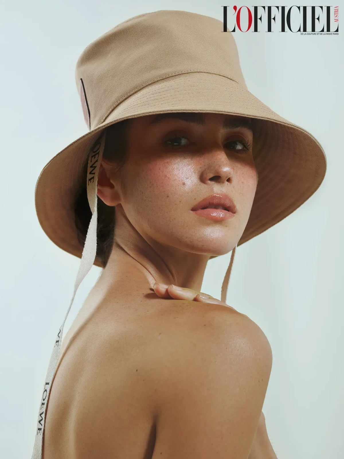 L’Officiel portrait of a freckled model wearing a beige bucket hat