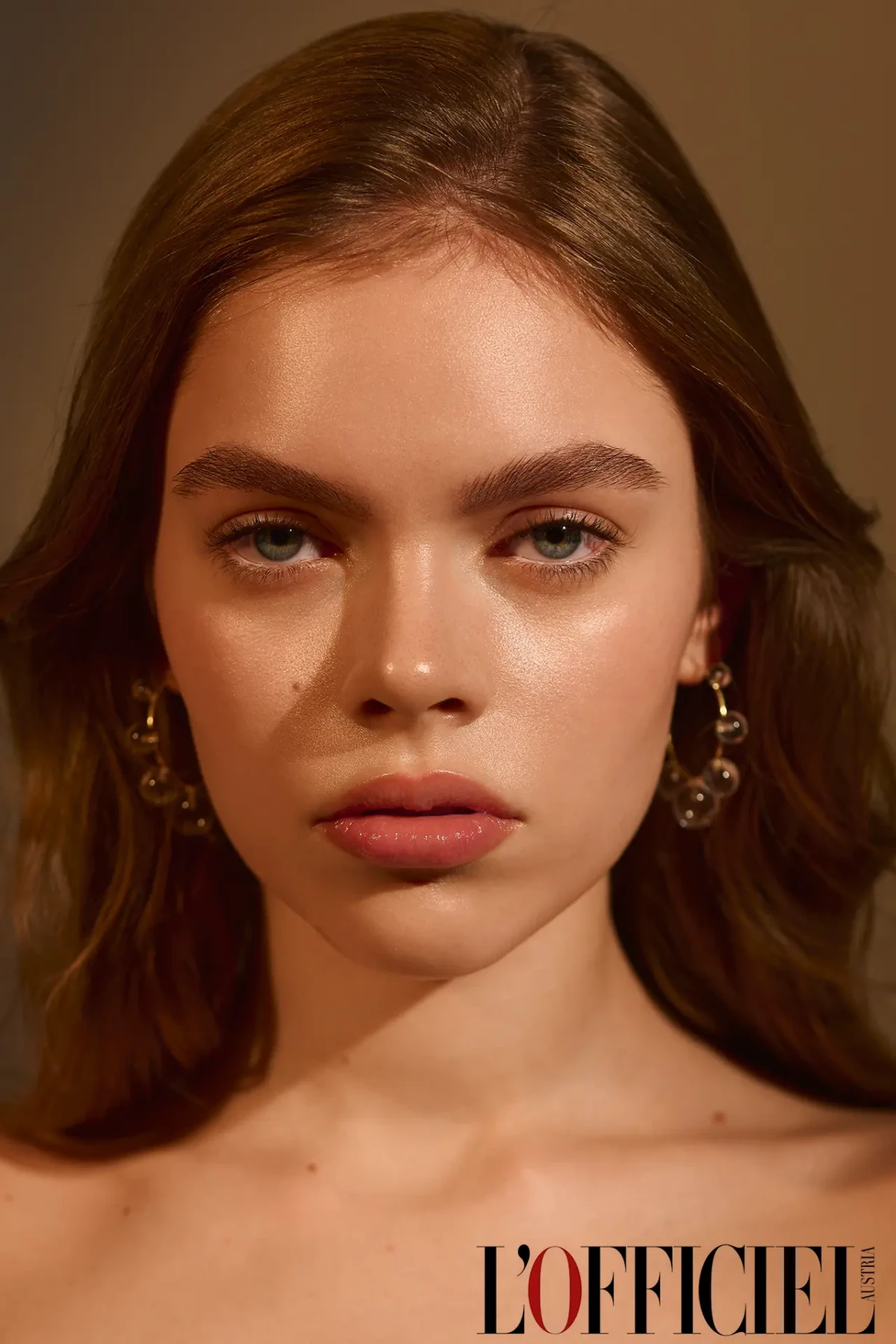 L’Officiel beauty portrait with bare shoulders, soft light and gold earrings